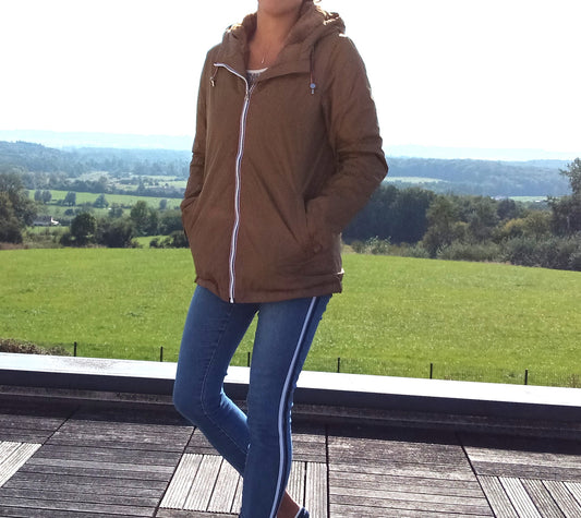 Woman wearing camel Laura Jo raincoat from Le Petit Placard, outdoors on wooden terrace