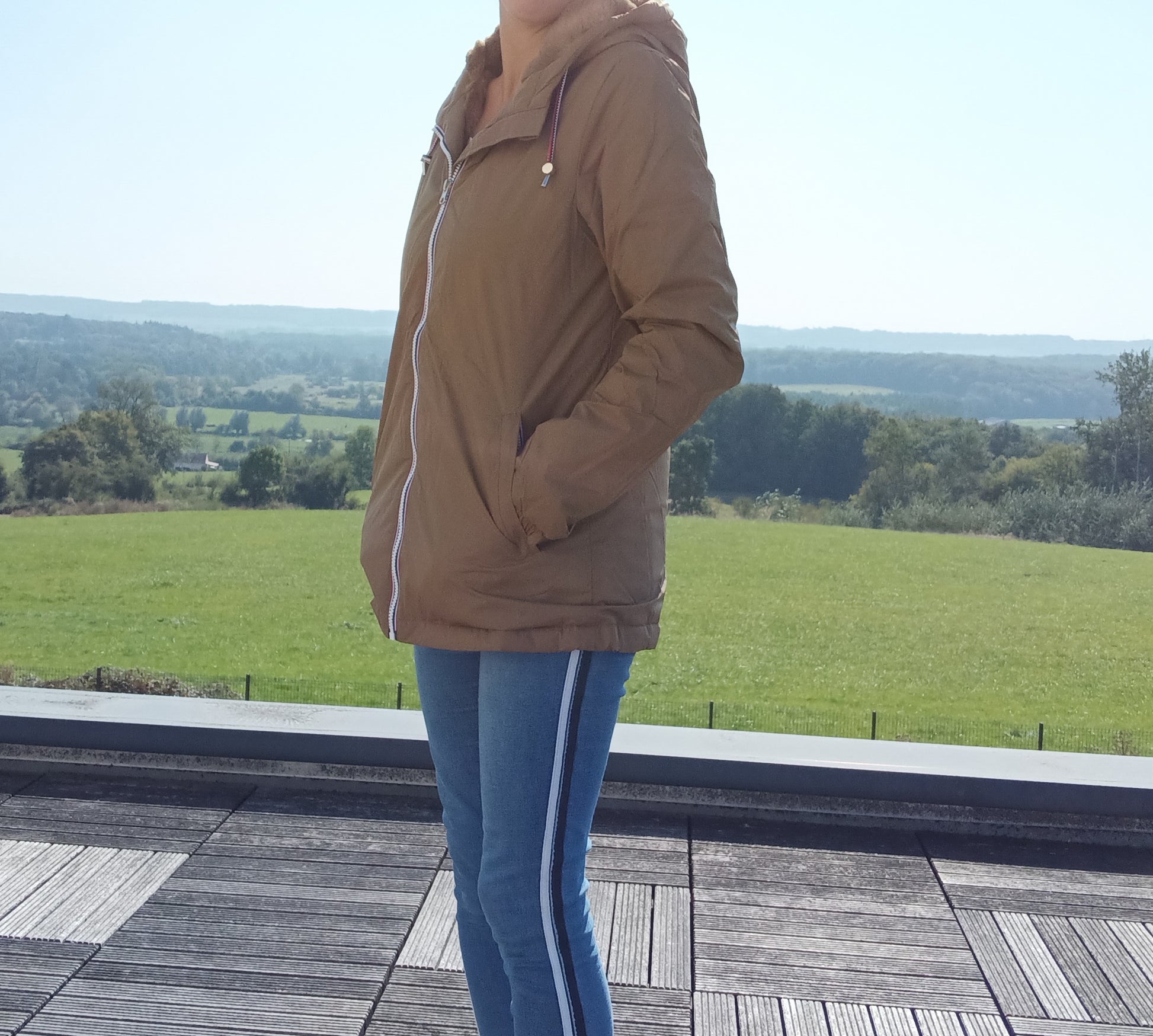 Woman wearing a camel Laura Jo raincoat and jeans outdoors, Le Petit Placard collection