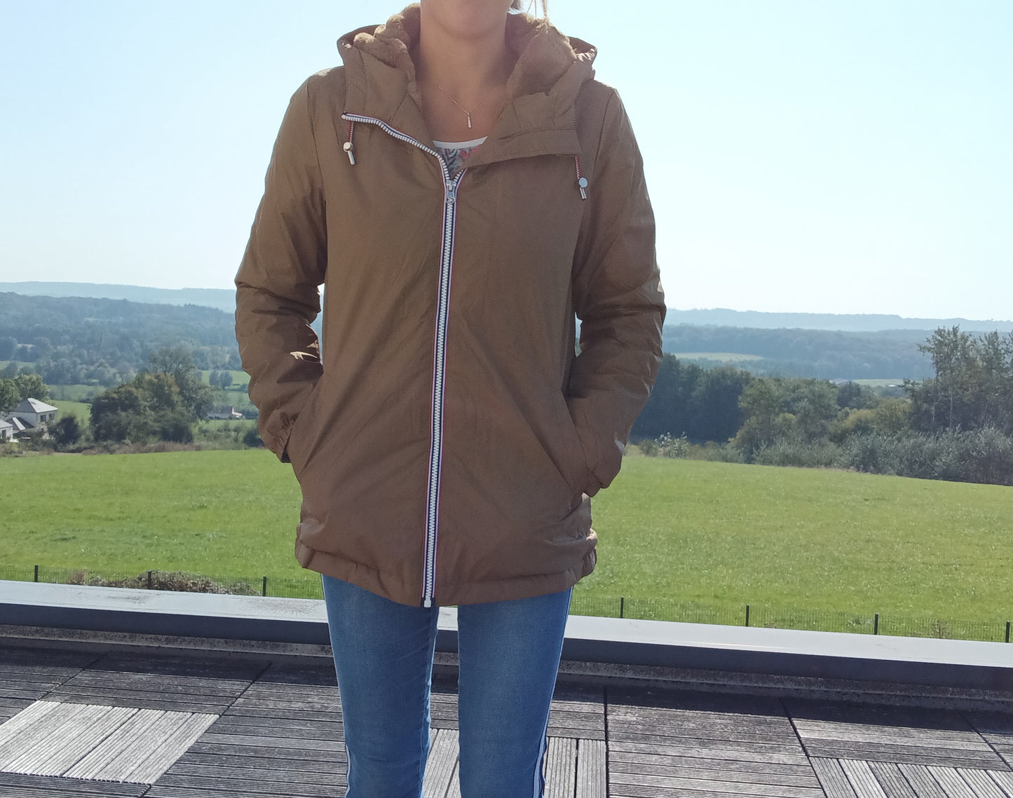 Woman wearing Laura Jo camel raincoat, blue jeans, outdoors, Le Petit Placard style