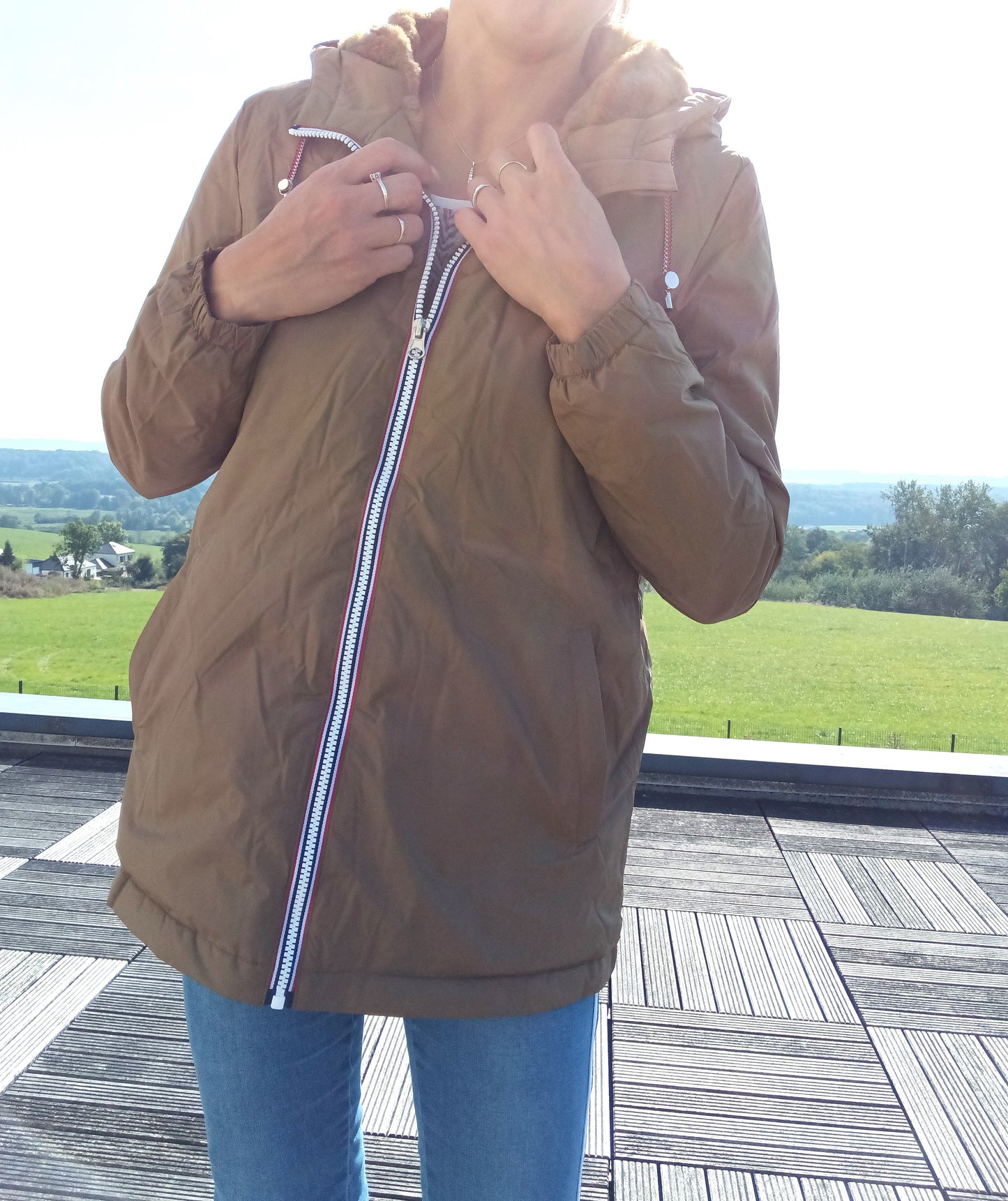Woman wearing camel Laura Jo raincoat from Le Petit Placard, outdoors on terrace