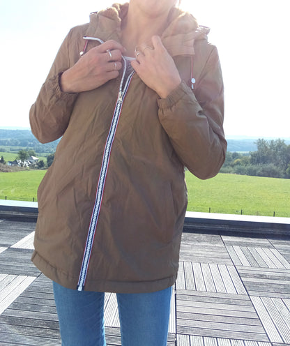 Woman wearing camel Laura Jo raincoat from Le Petit Placard, outdoors on terrace