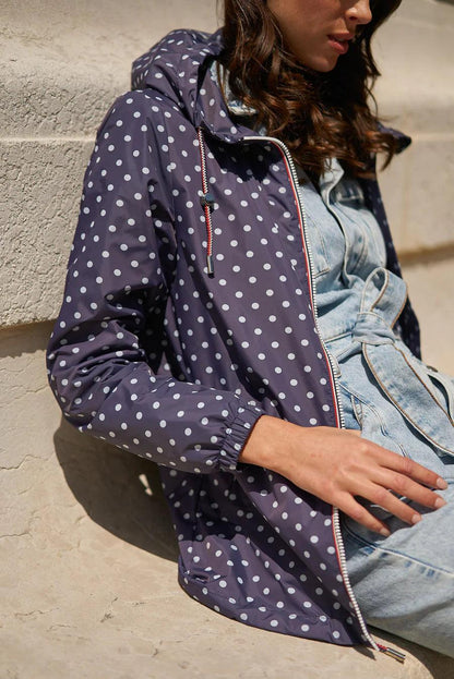 Woman wearing a navy blue polka dot Laura Jo raincoat from Le Petit Placard, seated outdoors