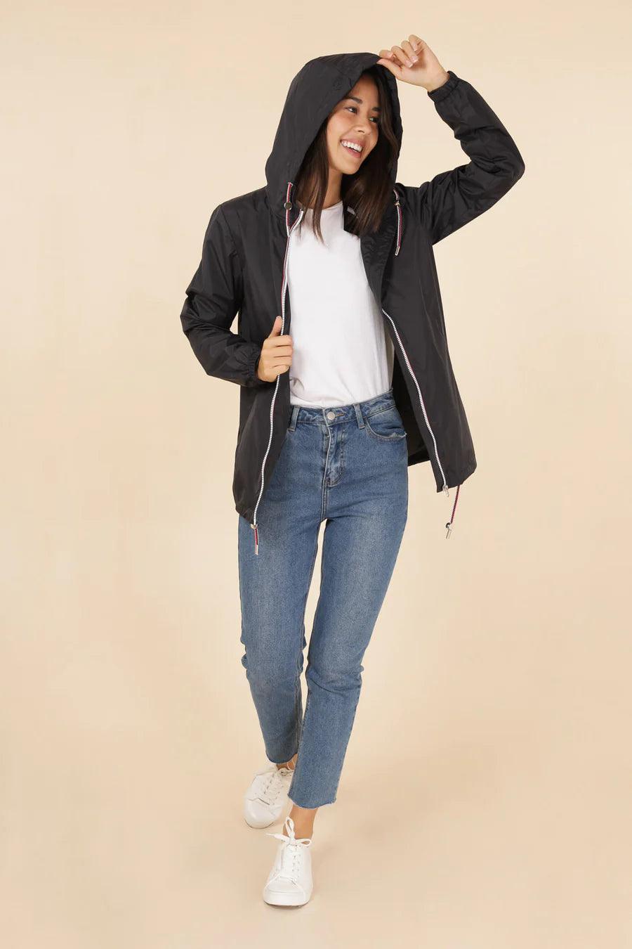 Woman wearing Laura Jo black mid-season raincoat, white t-shirt, jeans, and sneakers