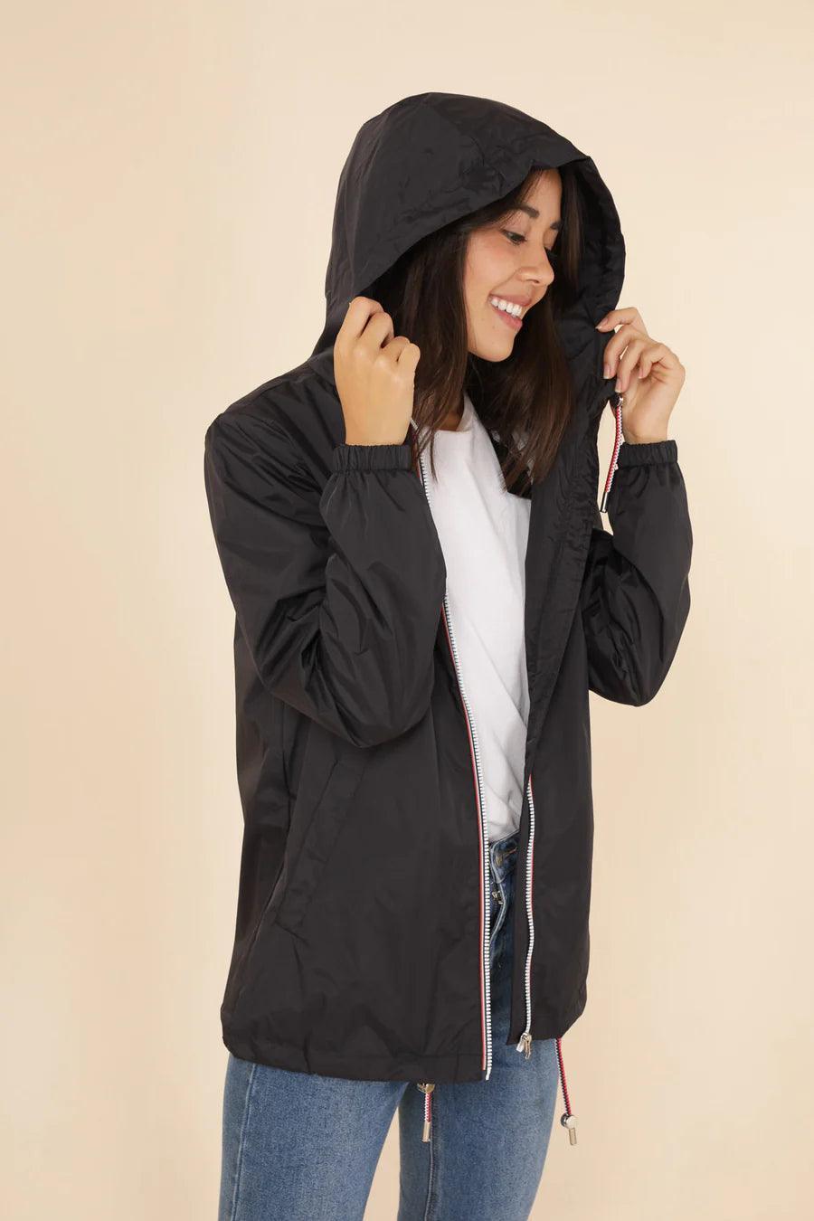 Woman wearing black Laura Jo raincoat with hood, white shirt and jeans, Le Petit Placard