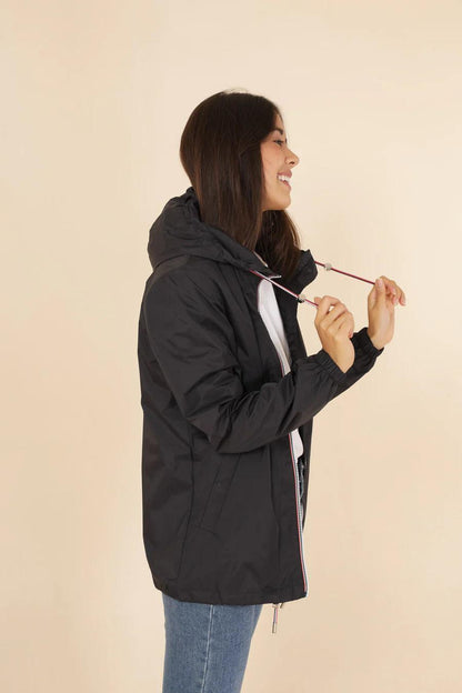 Woman wearing black Laura Jo raincoat from Le Petit Placard, side view, beige background