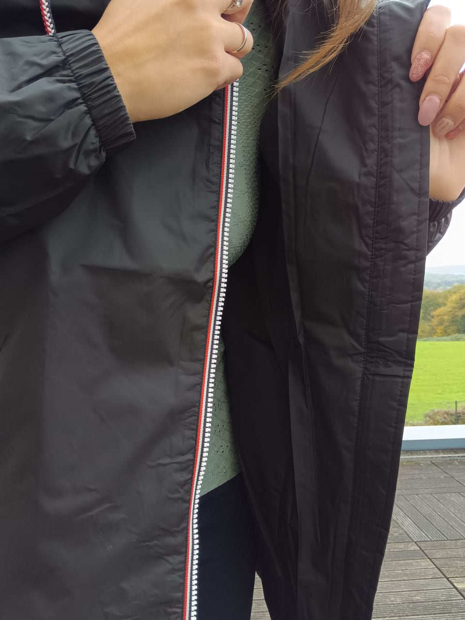 Close-up of person wearing Laura Jo black waterproof mid-season coat, Le Petit Placard