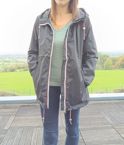 Woman wearing Laura Jo black rain jacket, standing outdoors on wooden terrace, Le Petit Placard