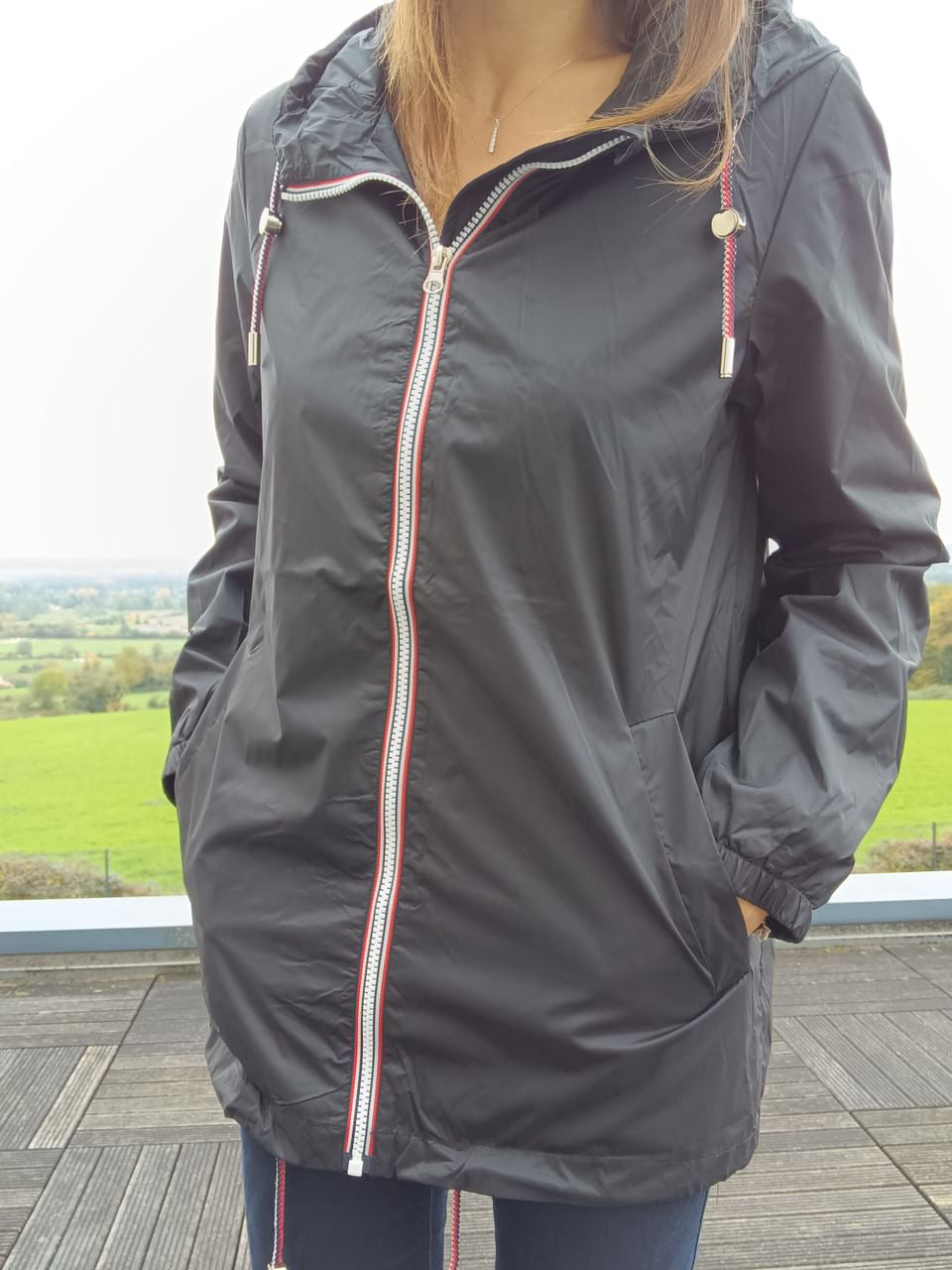 Black Laura Jo mid-season raincoat with hood, outdoor setting, Le Petit Placard