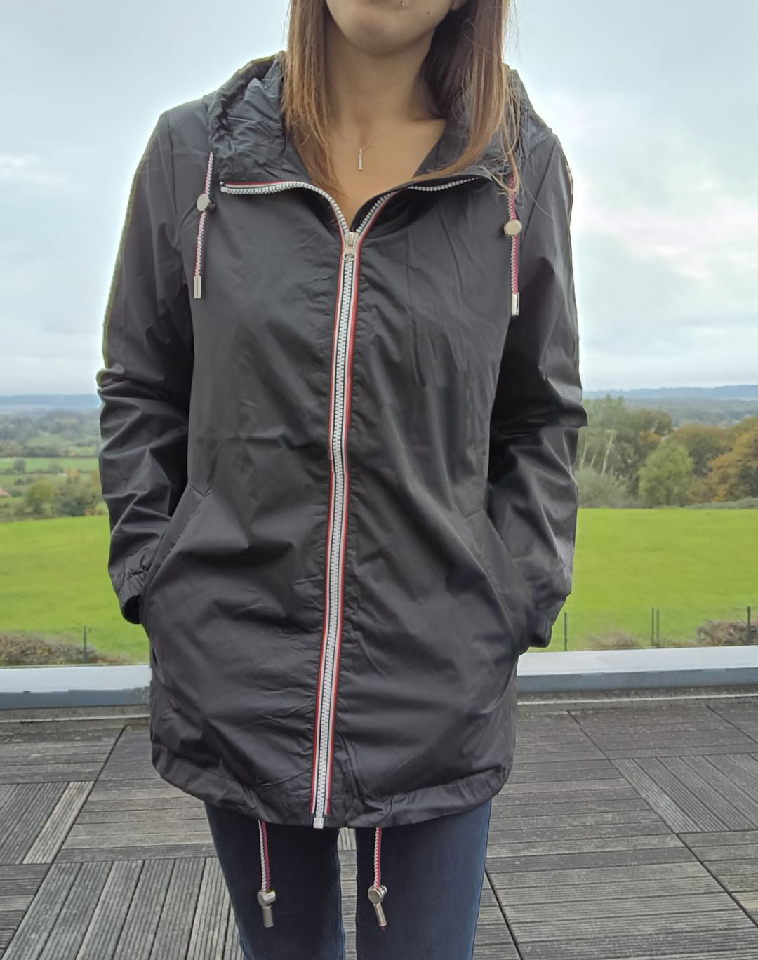 Woman wearing a black Laura Jo mid-length raincoat on terrace, Le Petit Placard collection