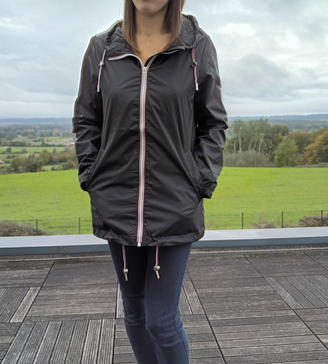 Woman wearing a black Laura Jo mid-length raincoat outdoors, Le Petit Placard collection