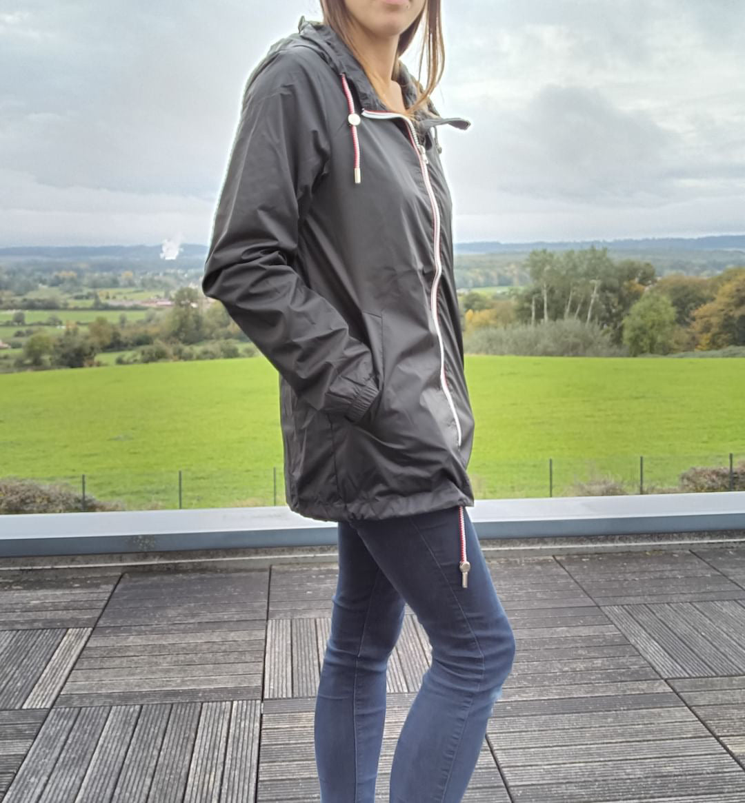 Woman wearing Laura Jo black raincoat and jeans on terrace, countryside view, Le Petit Placard
