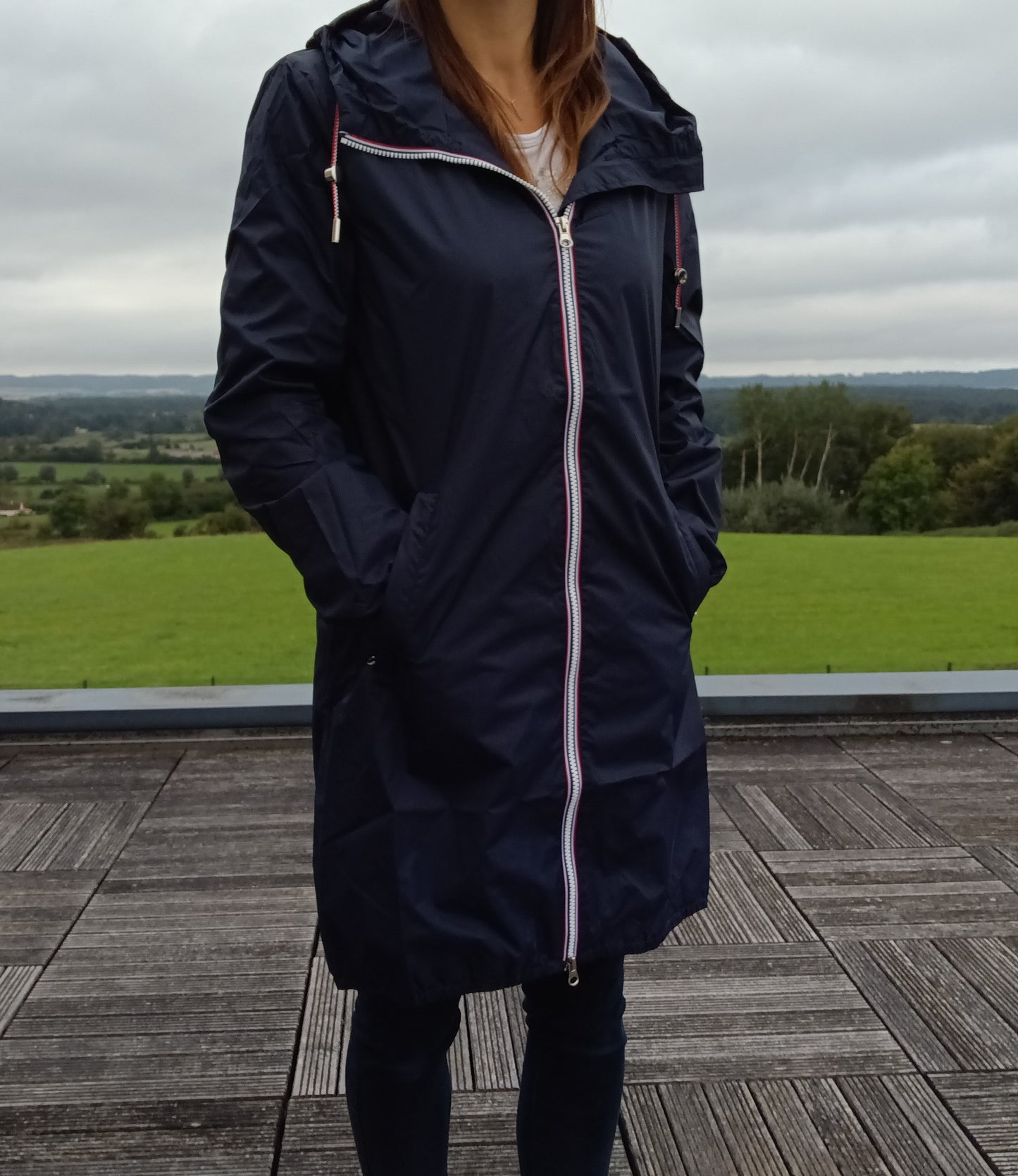 Parka manteau long bleu marine imperméable Laura Jo avec capuche et zip tricolore, porté par une femme