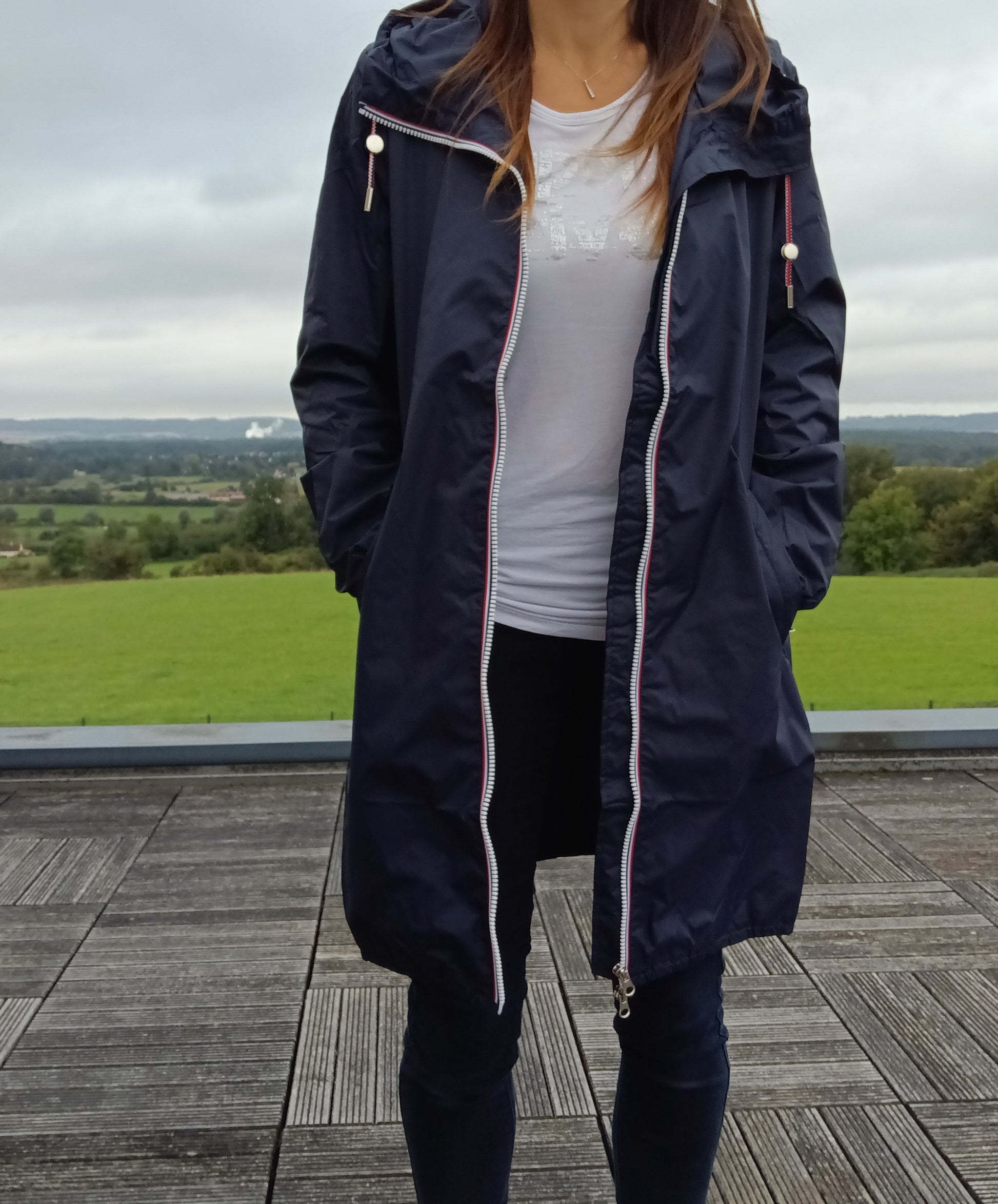 Femme portant un parka manteau long bleu marine imperméable Laura Jo à capuche, zip bicolore, coupe fine légère