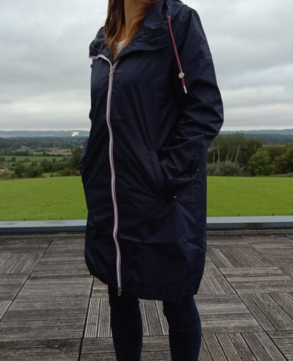Femme portant le parka manteau long bleu marine imperméable Laura Jo avec capuche et zip tricolore, en extérieur