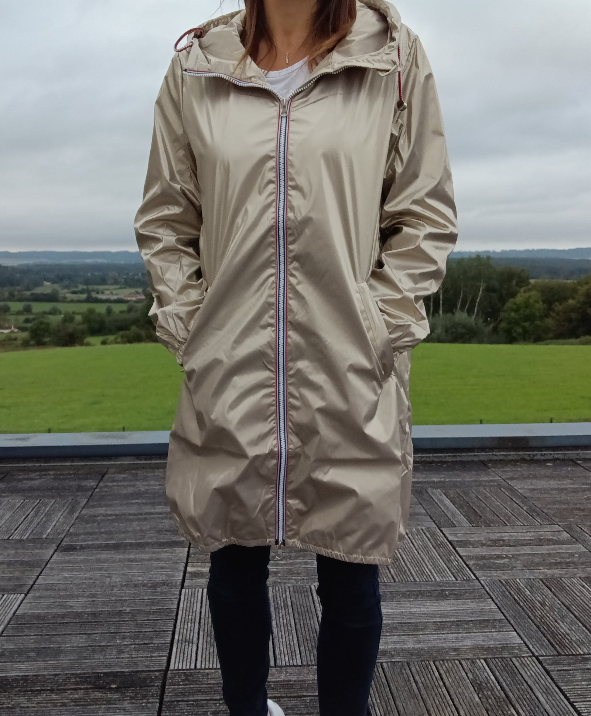 Parka manteau long imperméable doré Laura Jo porté par une femme, coupe fine avec capuche et zip tricolore