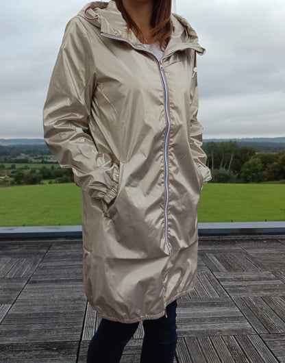 Parka manteau long imperméable doré Laura Jo à capuche et zip tricolore, porté par une femme en extérieur