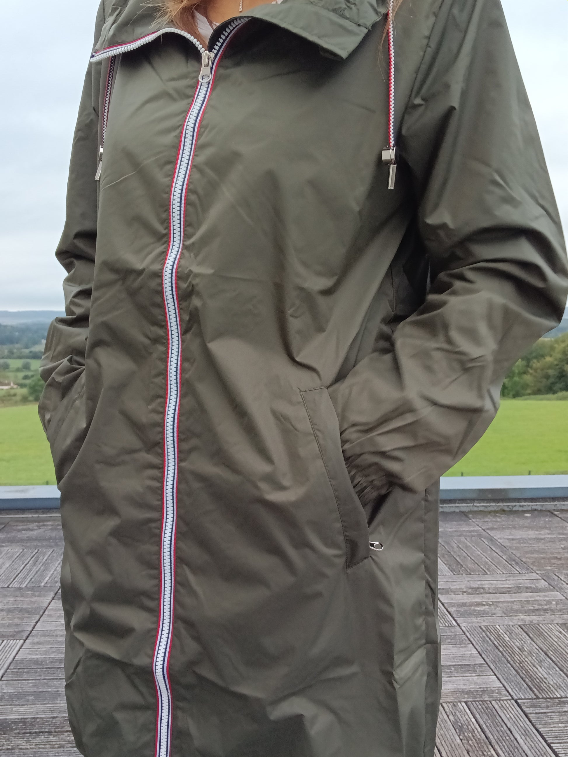 Woman wearing khaki Laura Jo raincoat with striped zipper outdoors at Le Petit Placard