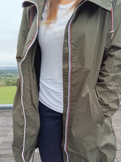 Woman wearing khaki Laura Jo raincoat, white t-shirt, outdoors at Le Petit Placard