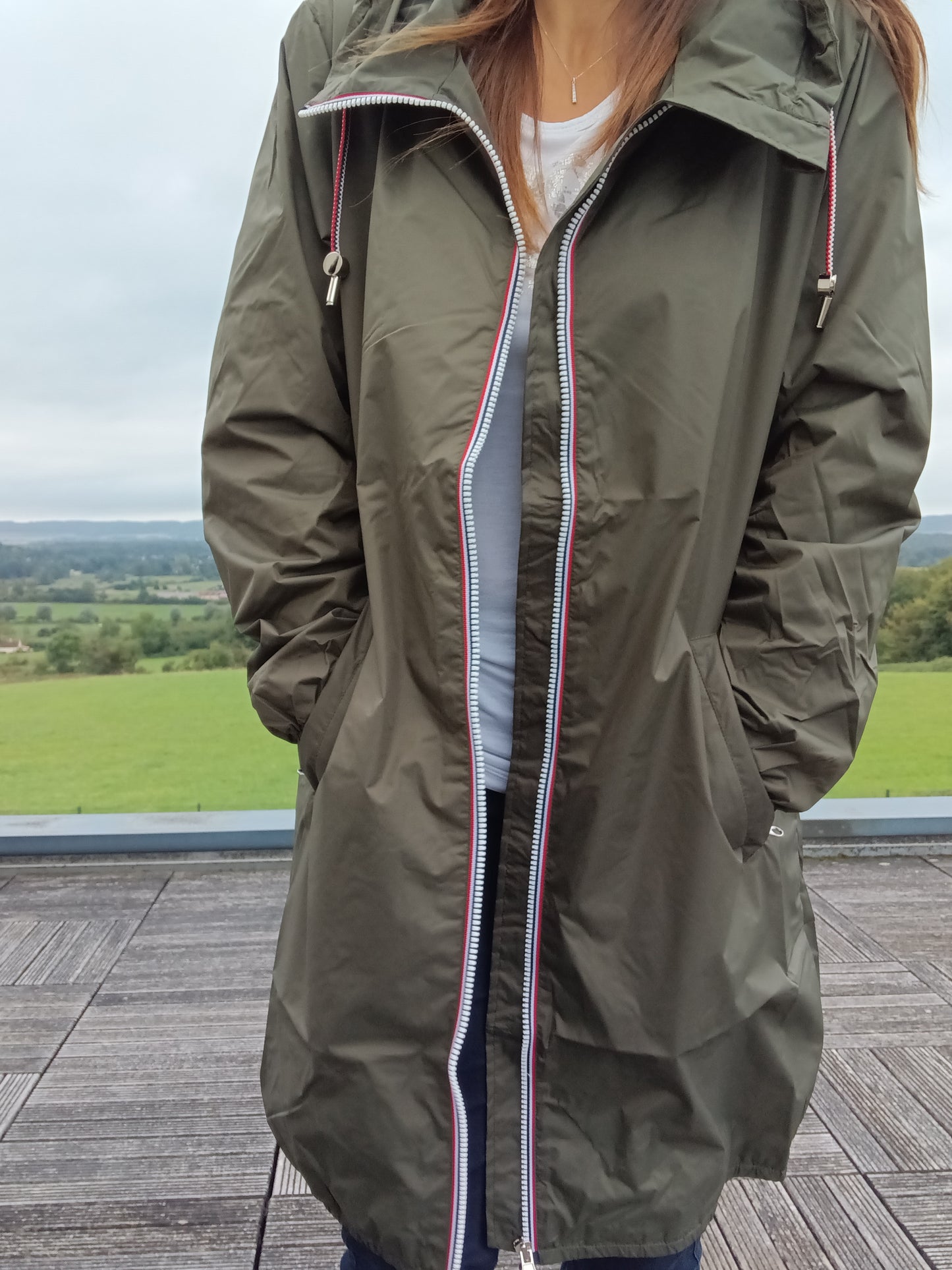 Woman wearing khaki Laura Jo raincoat from Le Petit Placard, outdoor terrace view