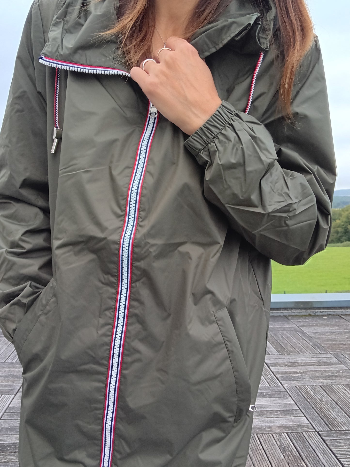 Woman wearing khaki Laura Jo raincoat with striped zipper detail outdoors, Le Petit Placard