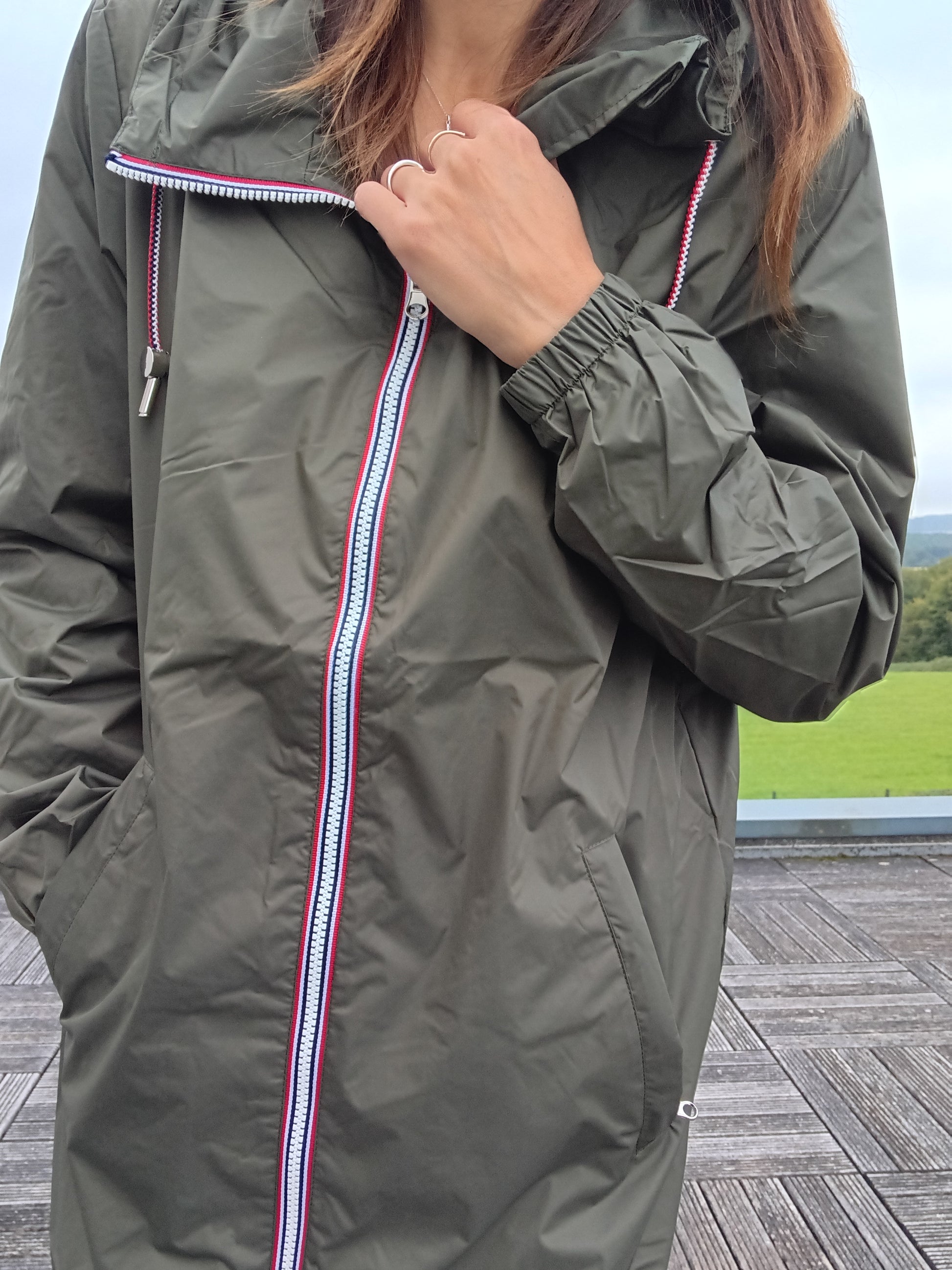 Woman wearing khaki Laura Jo raincoat with striped zipper detail outdoors, Le Petit Placard