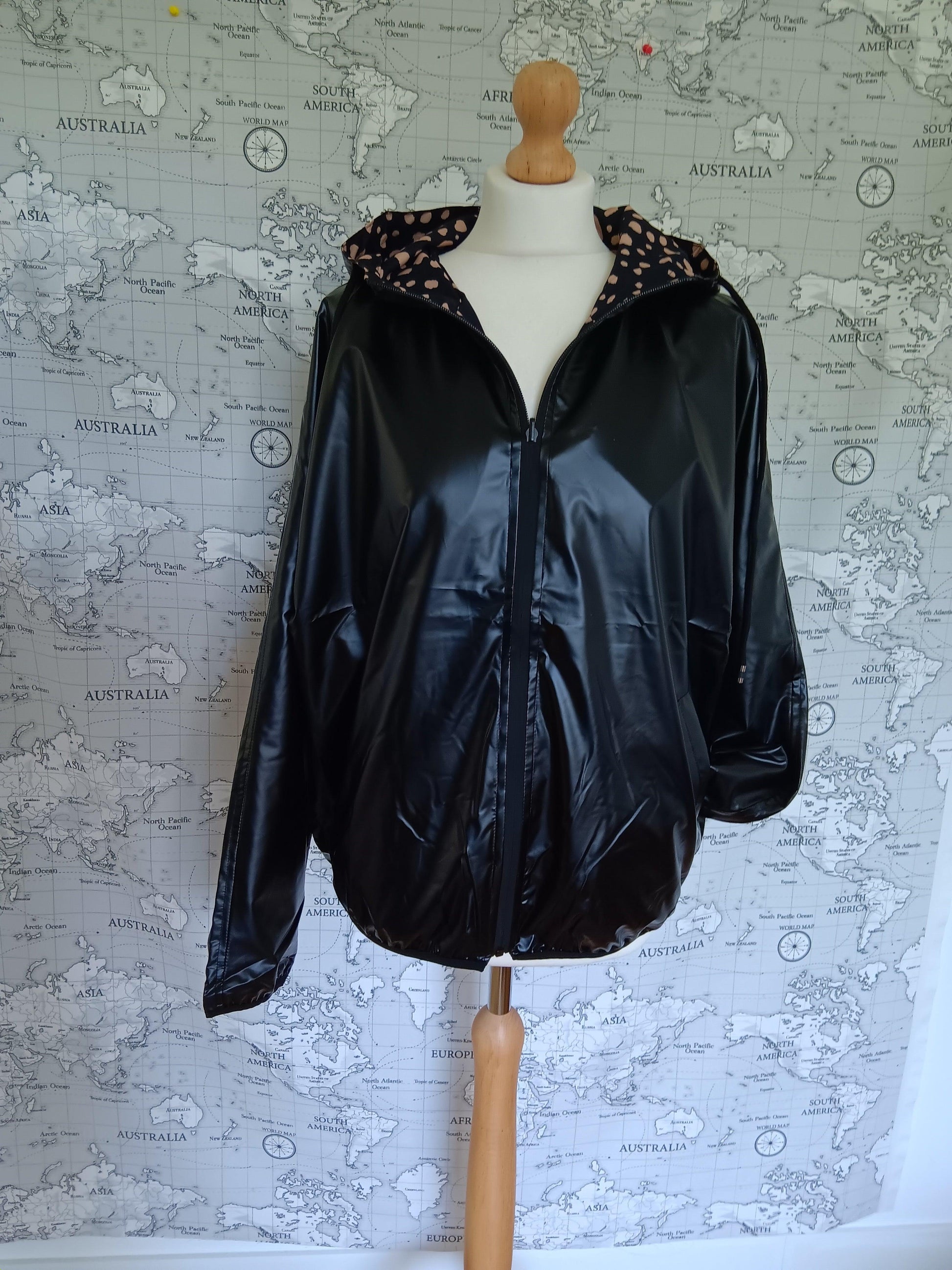 Black reversible raincoat with patterned hood from Le Petit Placard on mannequin, world map backdrop