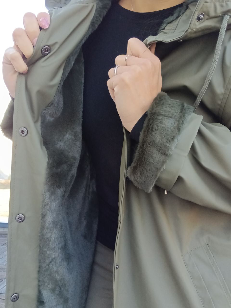 Woman displaying green Laura Jo raincoat with faux fur lining, Le Petit Placard fashion