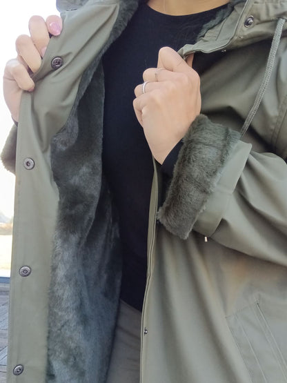 Woman displaying green Laura Jo raincoat with faux fur lining, Le Petit Placard fashion