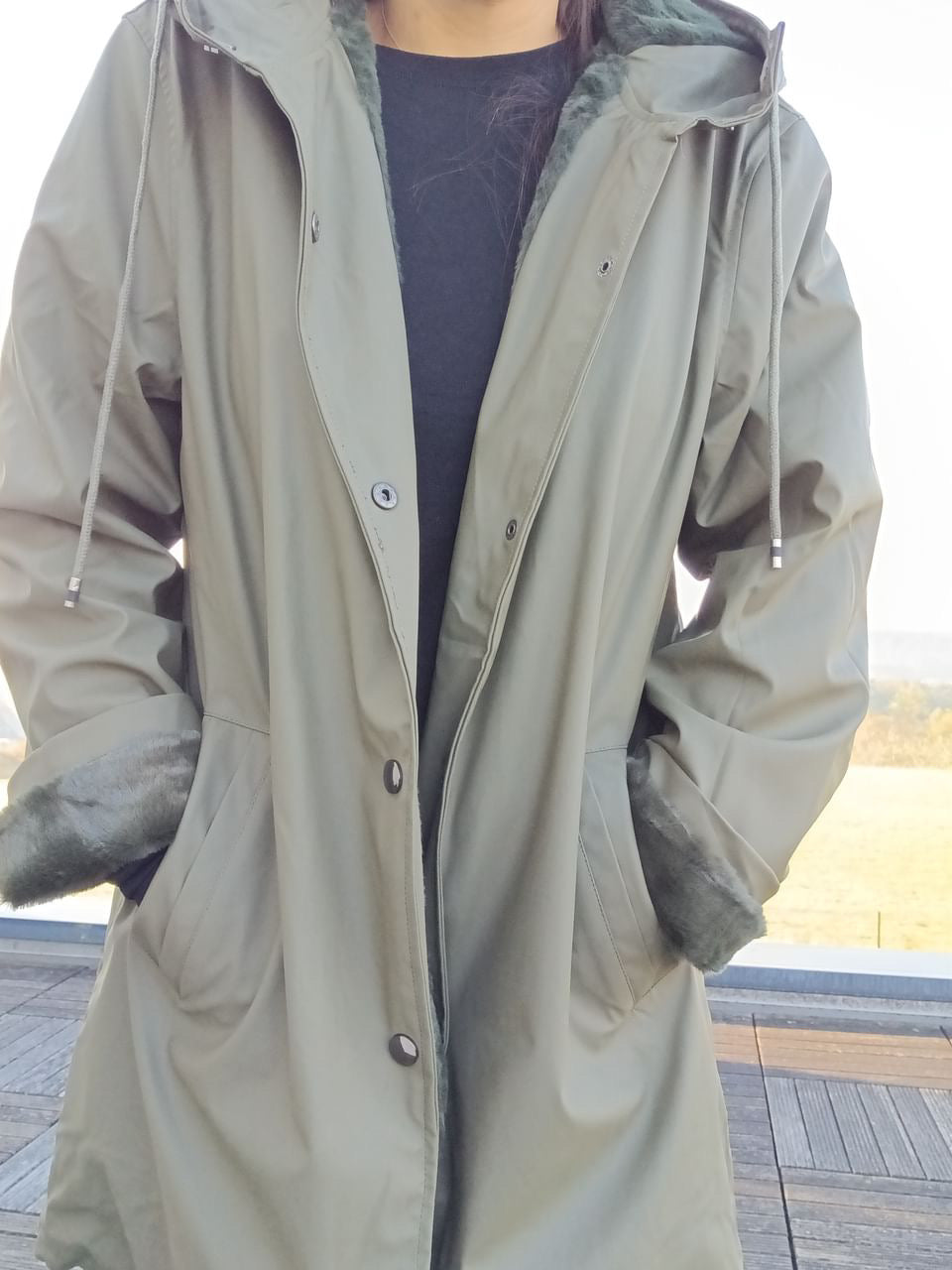 Woman wearing khaki Laura Jo raincoat with faux fur cuffs from Le Petit Placard outdoors
