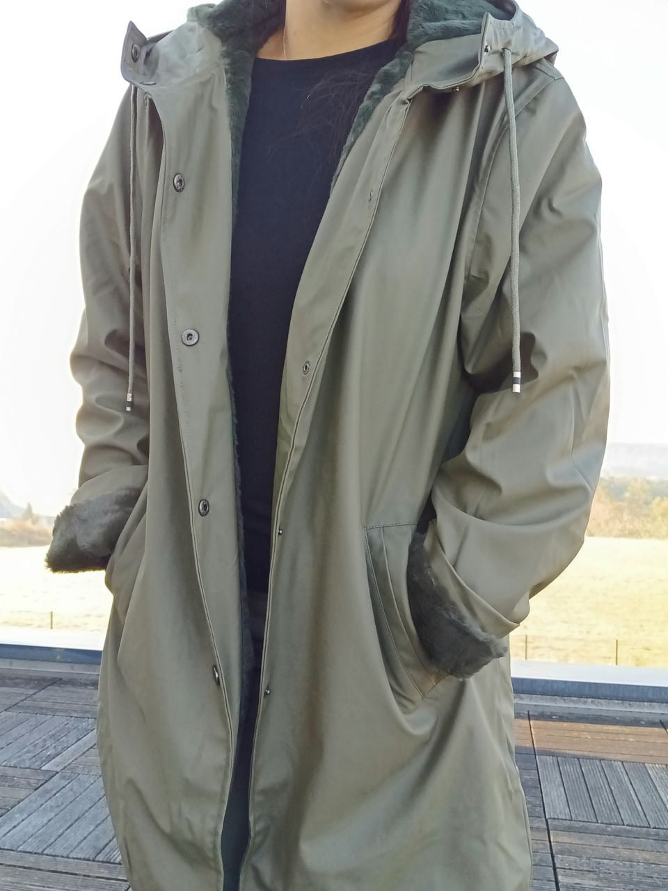 Long khaki waterproof parka with faux fur lining worn outdoors, Le Petit Placard