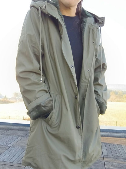 Woman wearing long khaki waterproof Laura Jo raincoat with faux fur lining outdoors