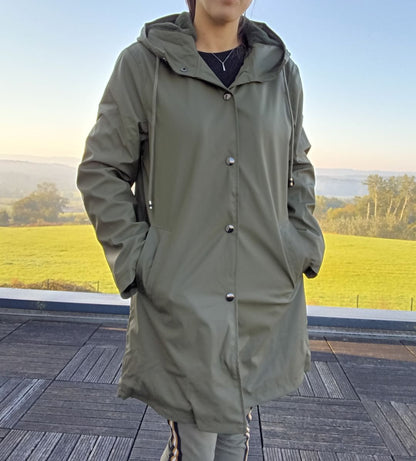 Woman wearing long khaki waterproof raincoat with hood outdoors, Le Petit Placard