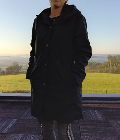 Woman wearing black Laura Jo raincoat outdoors, countryside background, Le Petit Placard