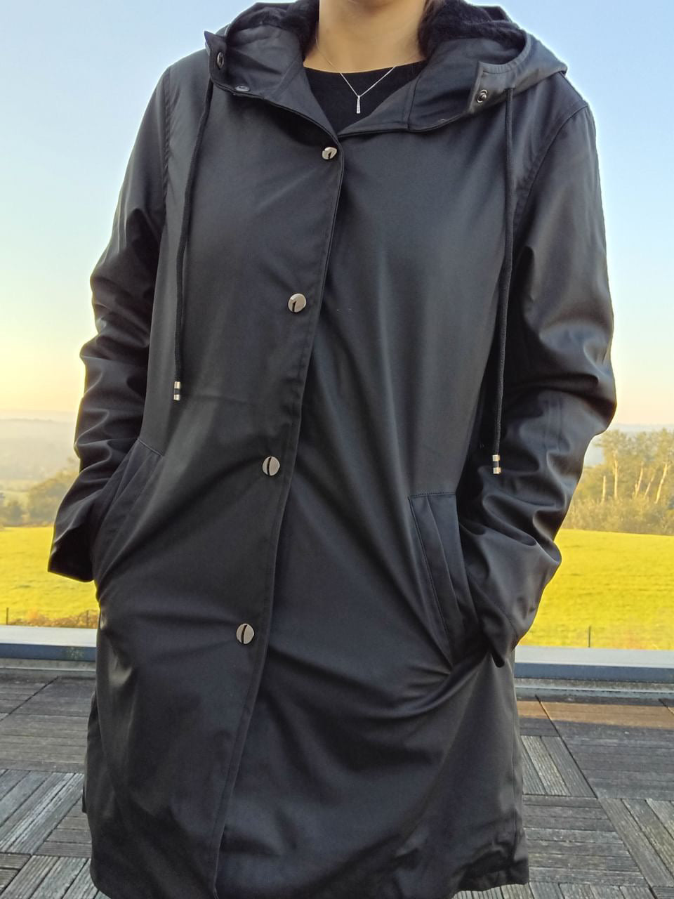 Laura Jo black raincoat with hood worn outdoors, Le Petit Placard fashion accessory
