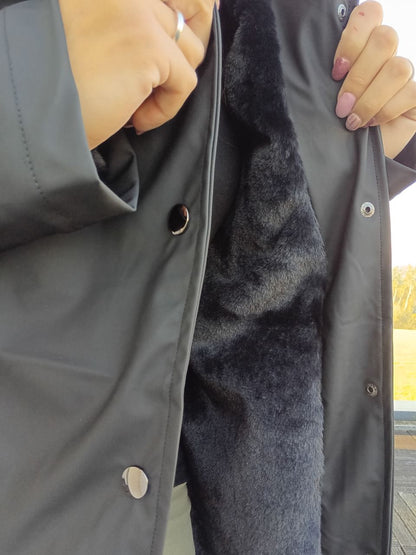 Black waterproof long coat with faux fur lining, shown open by hands, Le Petit Placard