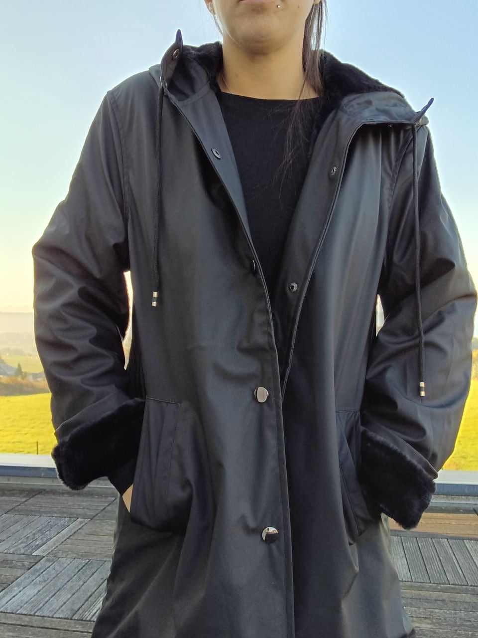 Long black waterproof Laura Jo coat with faux fur lining, modeled outdoors for Le Petit Placard