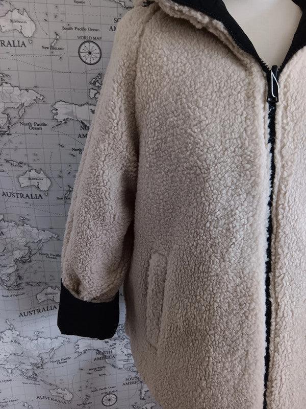 Reversible beige faux shearling jacket with black cuffs from Le Petit Placard, shown on a mannequin.