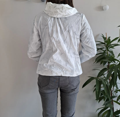 Back view of woman wearing white Laura Jo raincoat and grey jeans, indoor setting, Le Petit Placard