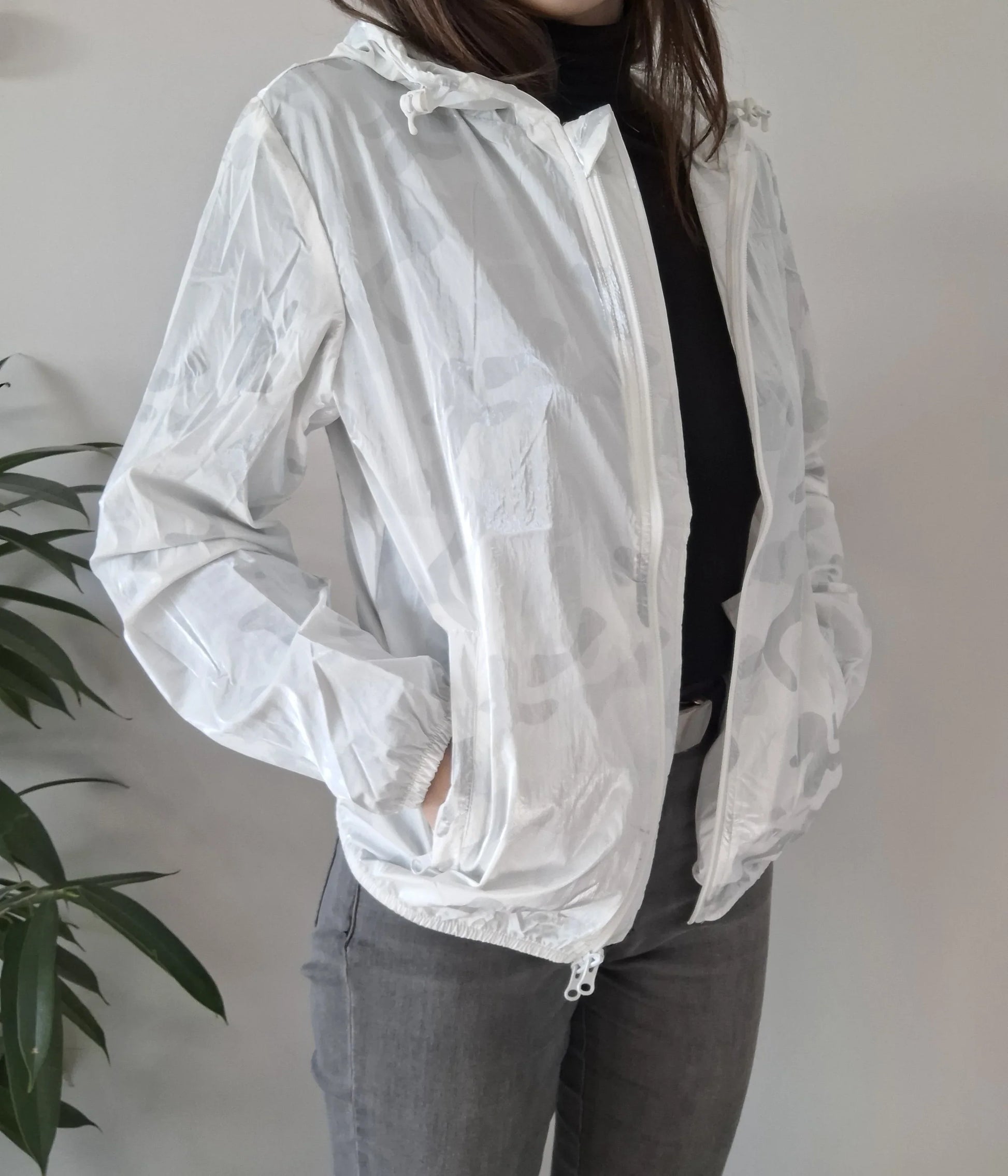 Woman wearing white Laura Jo raincoat from Le Petit Placard with hood and zipper pockets