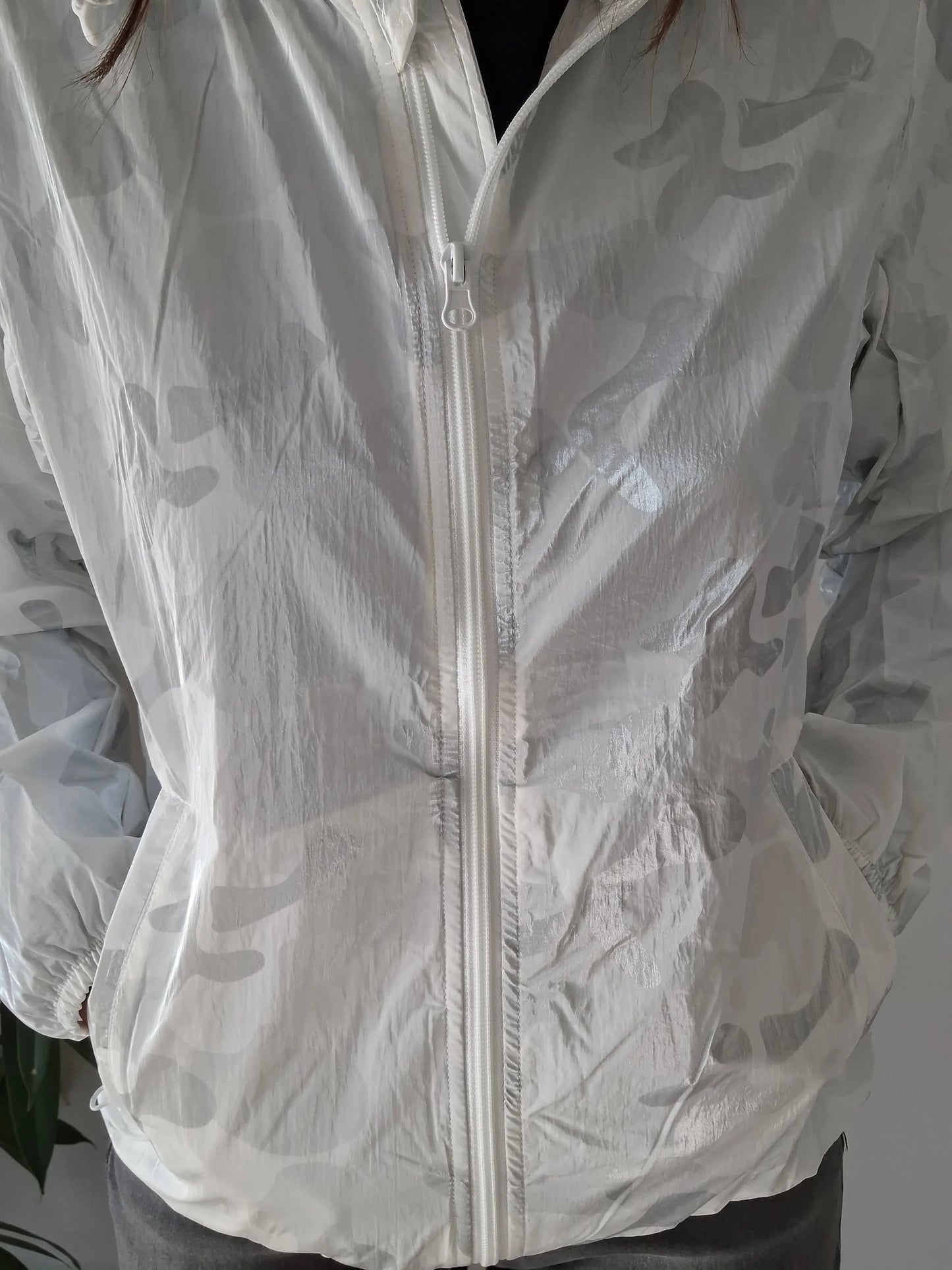 Close-up of a person wearing a light camouflage Laura Jo rain jacket from Le Petit Placard