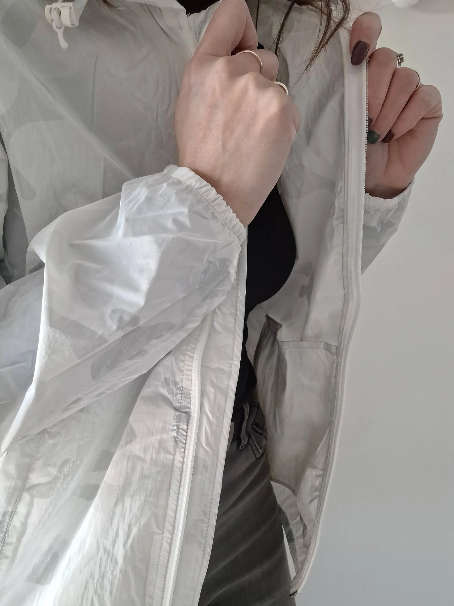 Woman wearing and zipping up a white Laura Jo raincoat, Le Petit Placard fashion.