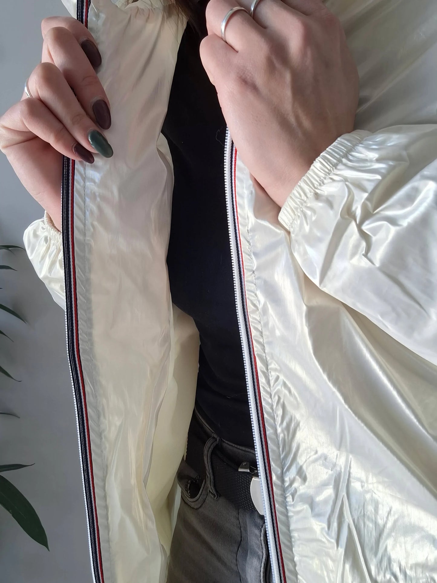 Woman wearing shiny white Laura Jo raincoat, black top, grey pants, Le Petit Placard fashion