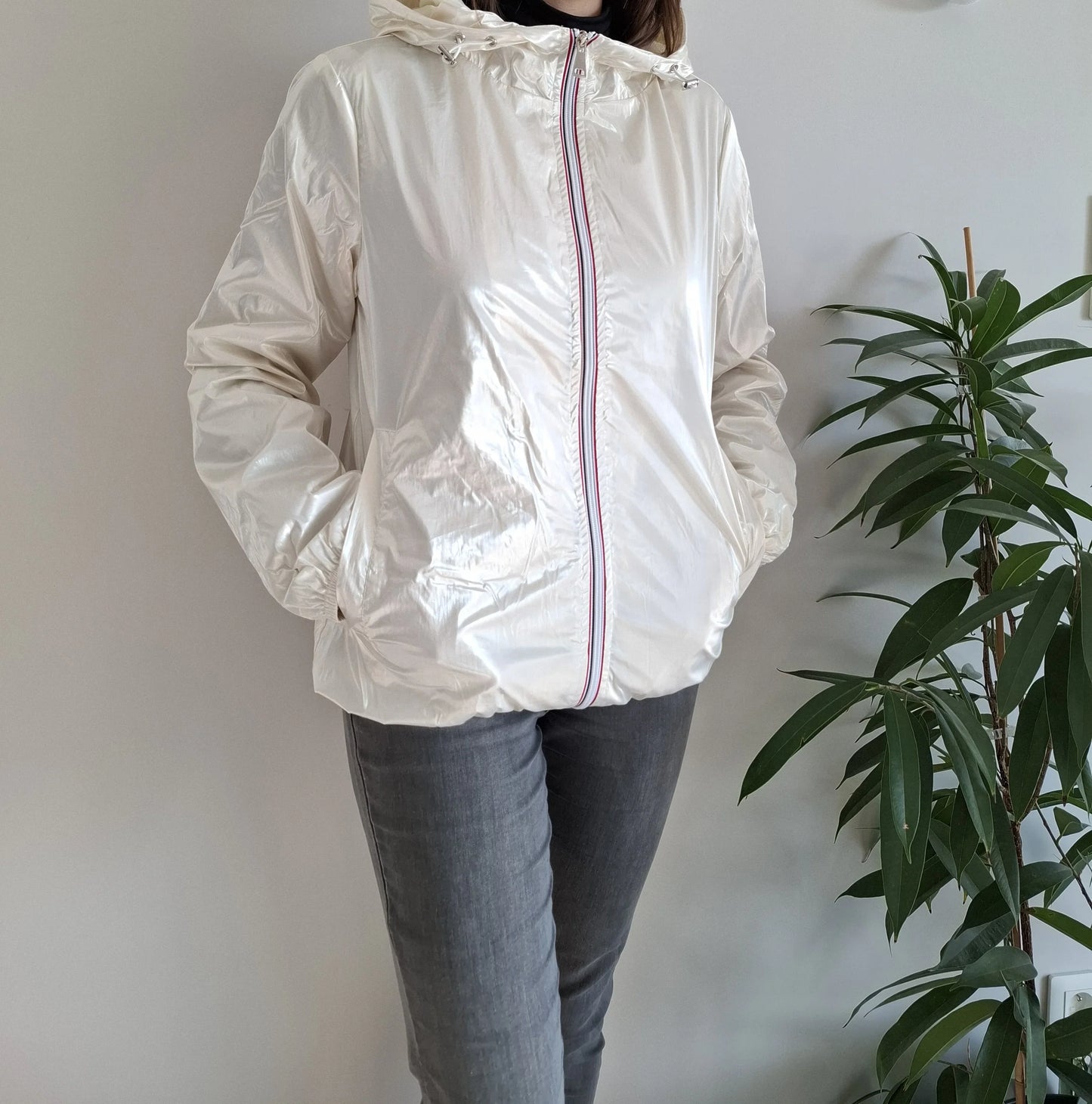 Woman wearing shiny white Laura Jo rain jacket from Le Petit Placard, standing indoors