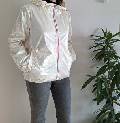 Woman wearing shiny white Laura Jo raincoat from Le Petit Placard, indoors by a green plant.