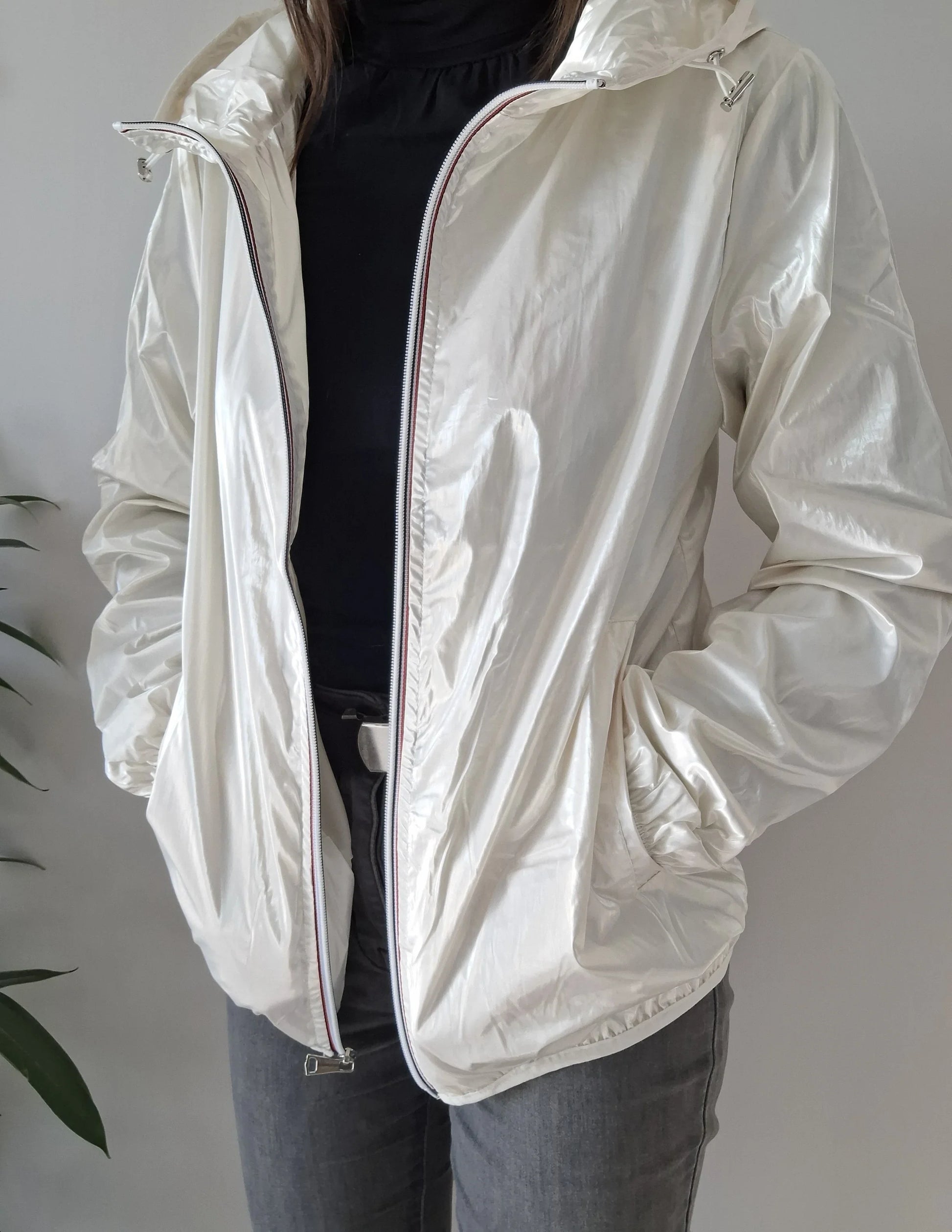 Woman wearing shiny white Laura Jo raincoat, black top, and grey jeans from Le Petit Placard