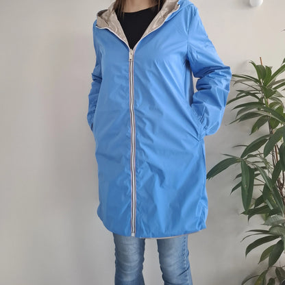Manteau long réversible imperméable bleu porté par une femme, côté bleu visible avec capuche dorée et fermeture éclair