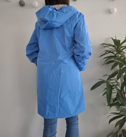 Vue de dos d'une femme portant le manteau long réversible imperméable bleu Melya Melody à capuche, longueur mi-cuisse