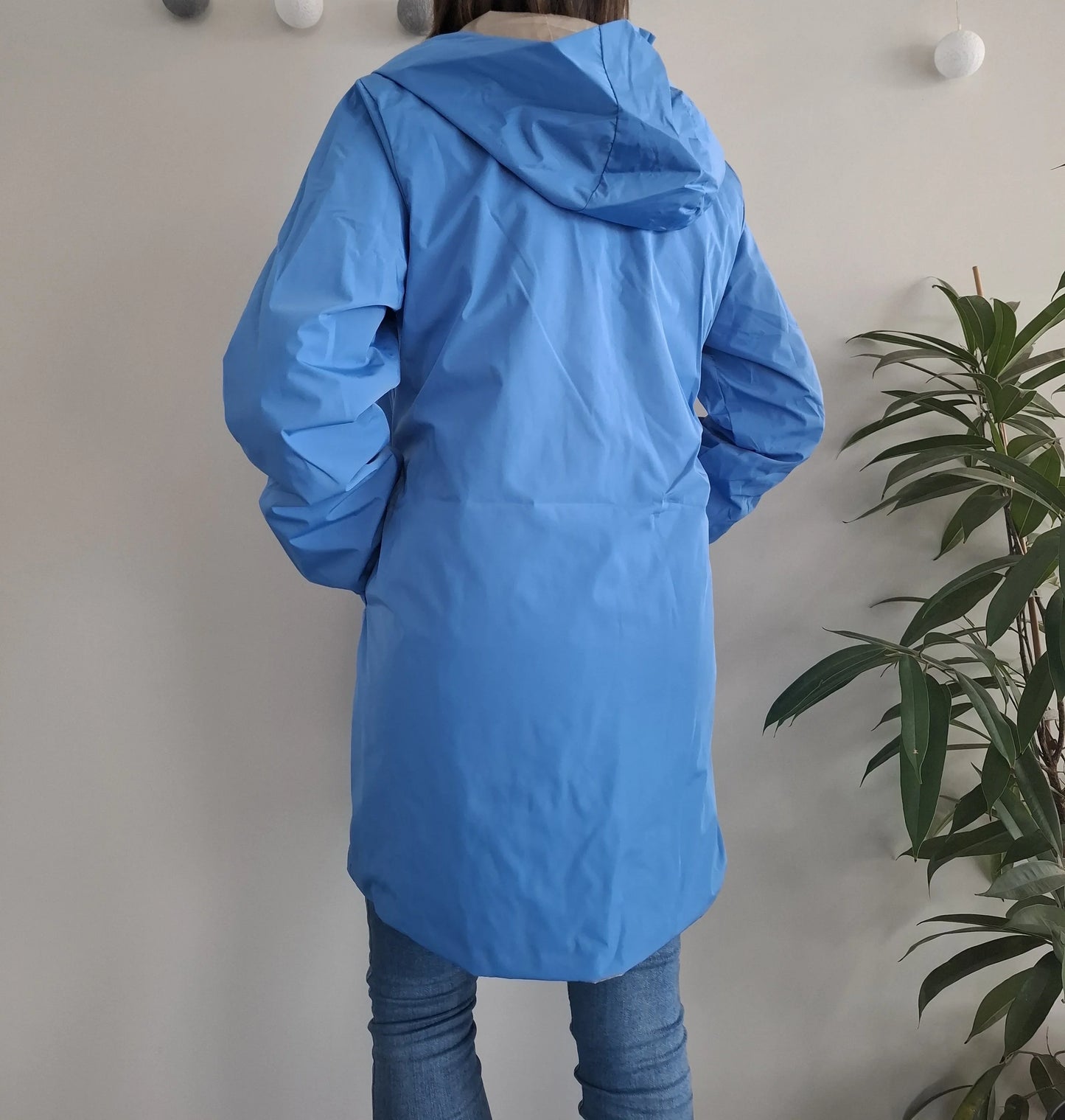 Vue de dos du manteau long réversible imperméable bleu Melya Melody à capuche, porté avec un jean