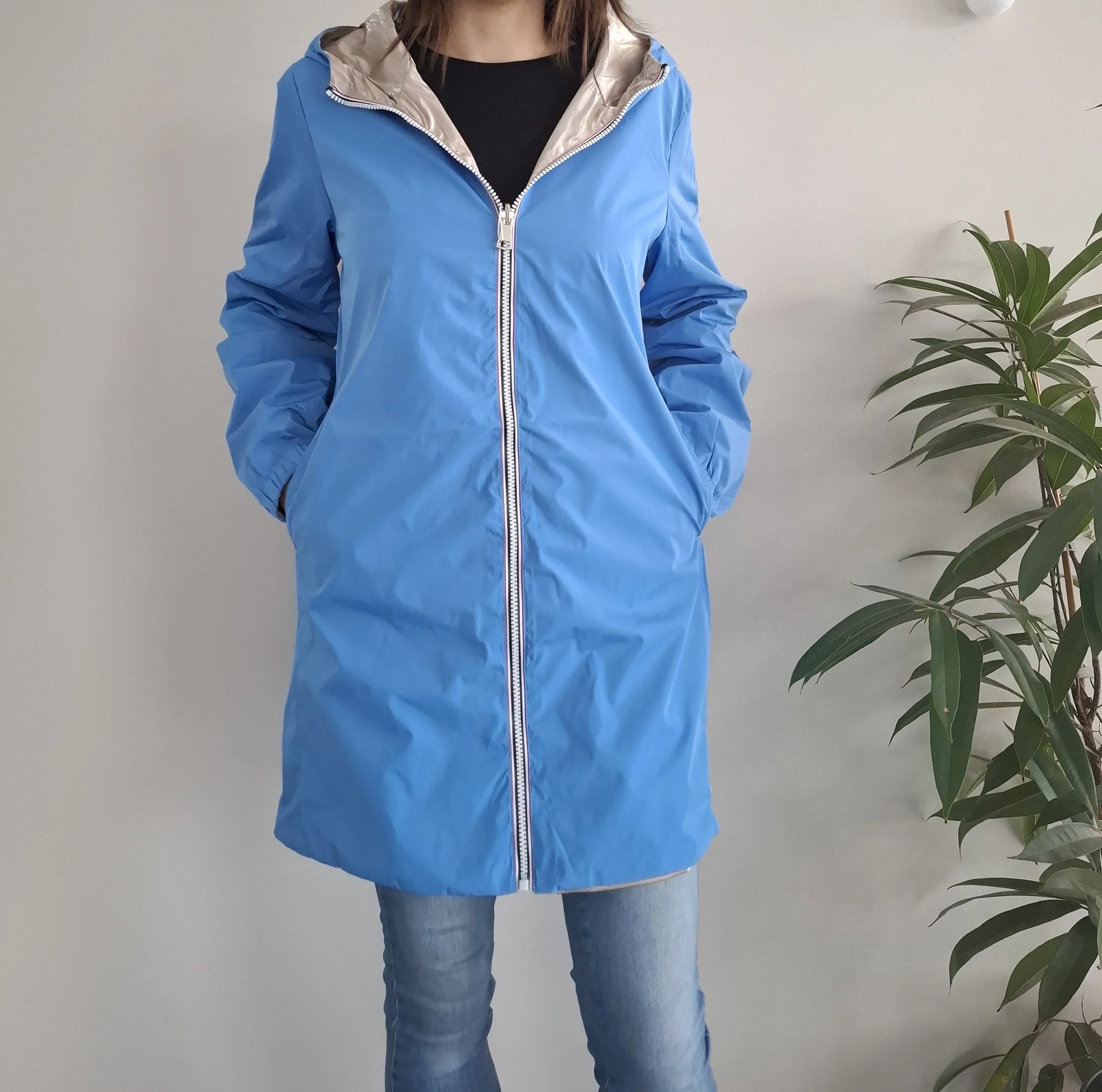 Manteau long réversible imperméable bleu et doré Melya Melody avec capuche et fermeture éclair, porté par une femme