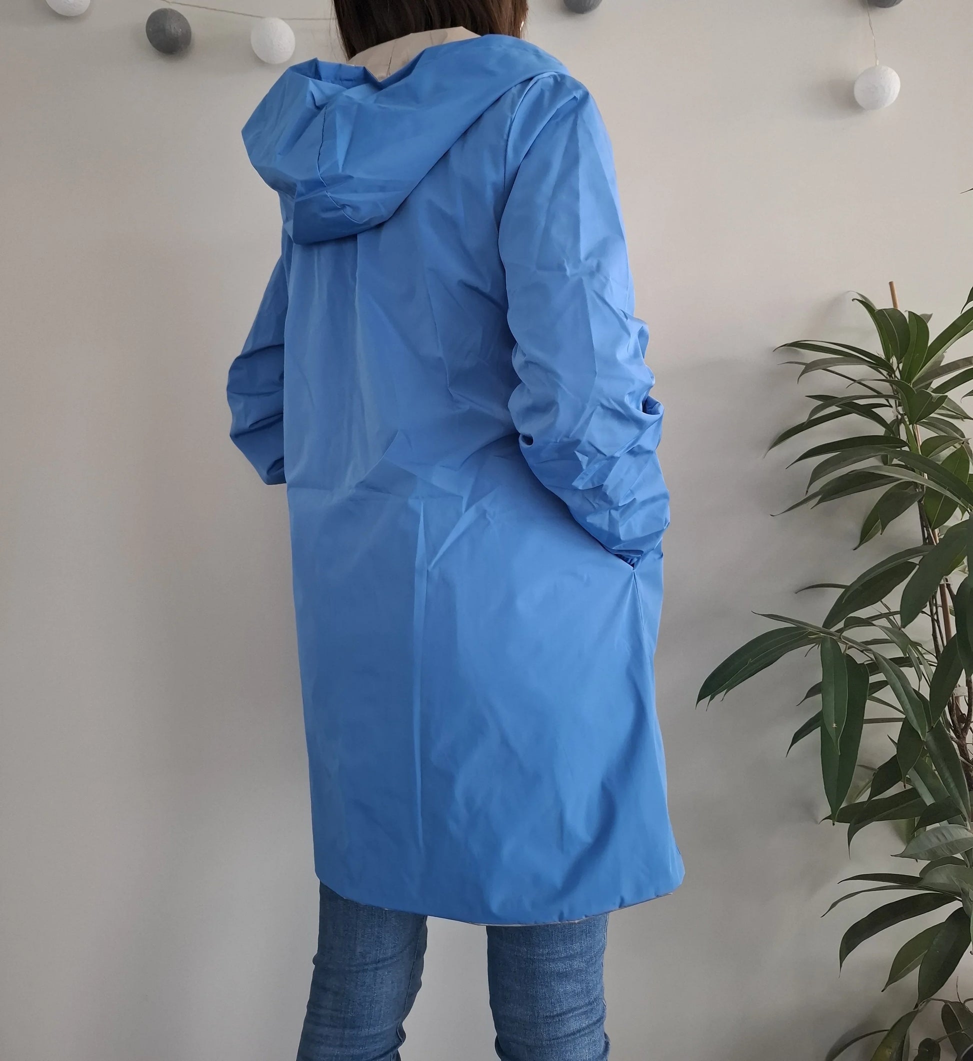 Femme portant le manteau long réversible imperméable bleu Melya Melody avec capuche, vue de dos, coupe mi-longue